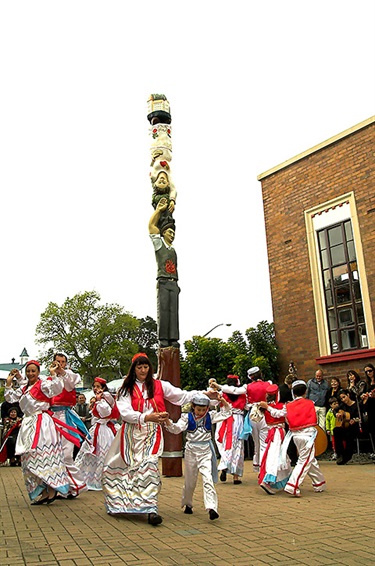 Picture of dancers in traditional Dalmatian costume dancing around the Dalmatian Pou.