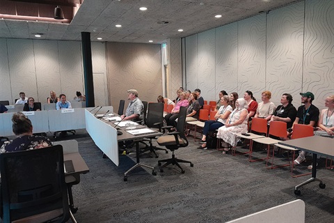 photo of council chambers with people sitting at the seats. 