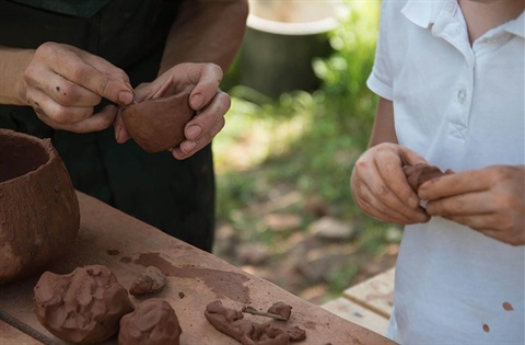 An adult and a child play with clay. 