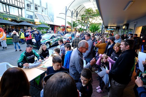 Crowds gather in the city centre and drivers sign autographs at a rally event. 