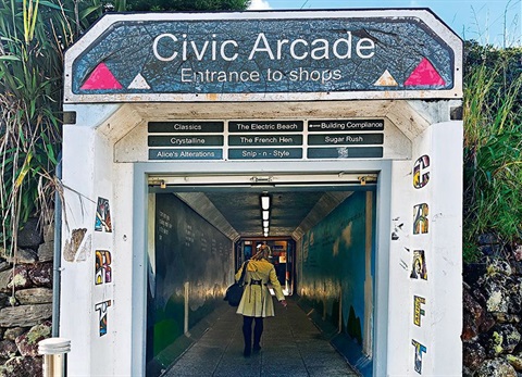 A photo of the entrance to the Civic Arcade taken from the Forum North carpark with a woman walking through the tunnel. 