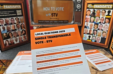 An information pamphlet about the electoral system being held up in the Elections Lounge. 