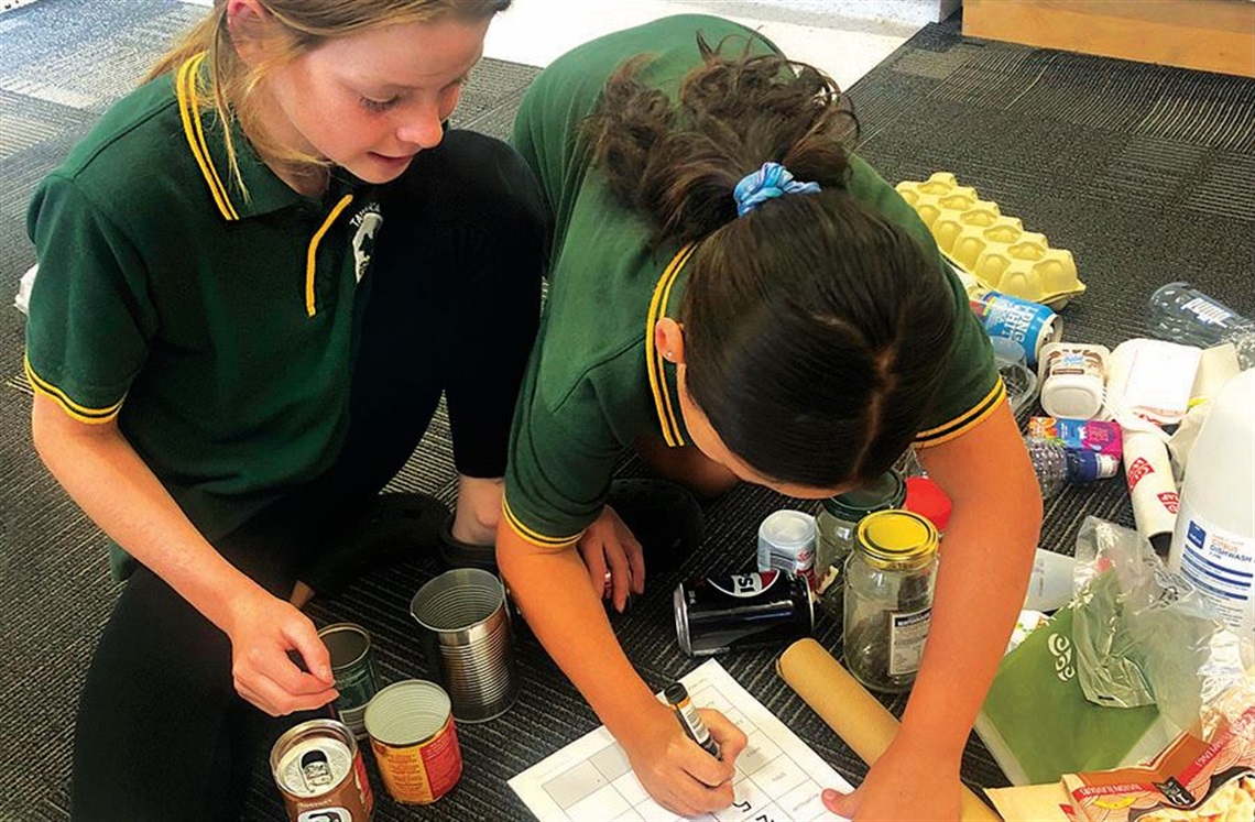Two female students busy at work in the classroom learning about resource management. 