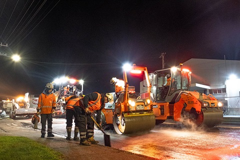 A roadworks crew at work on the road at night. 