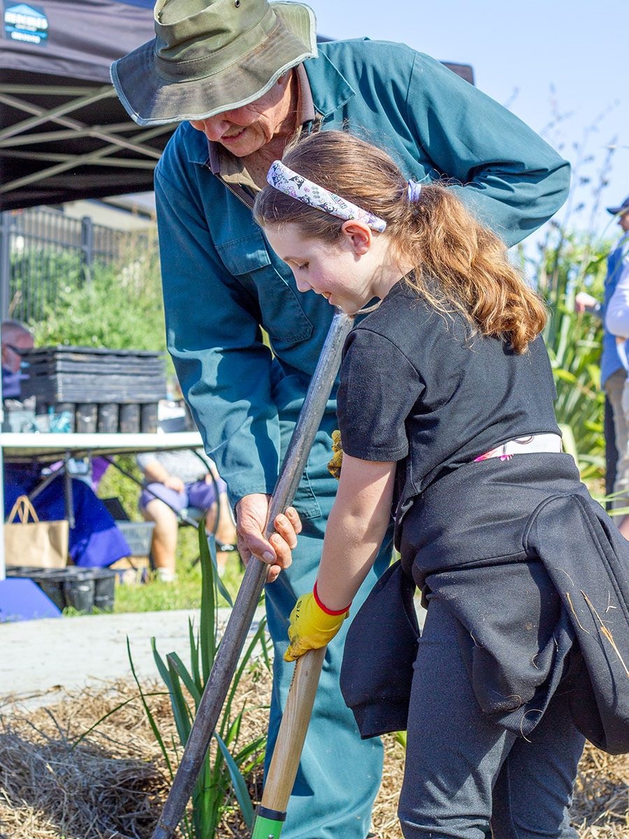 An older man and a young girl volunteering at a community planting day.