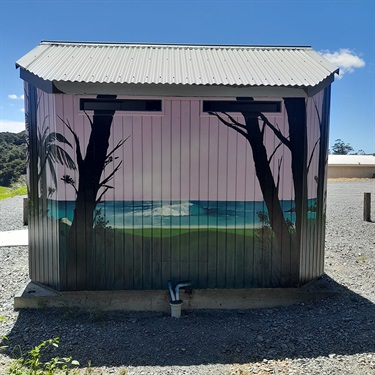 A photo of the back of the Parua Bay Community Centre public toilet block mural: The rolling waves of Ocean Beach keep the coastal vibes flowing.