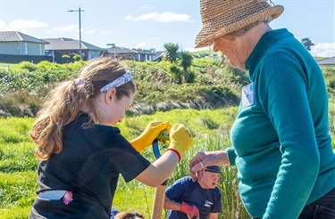 A young girl and an older woman dig at a wetlands planting day. 