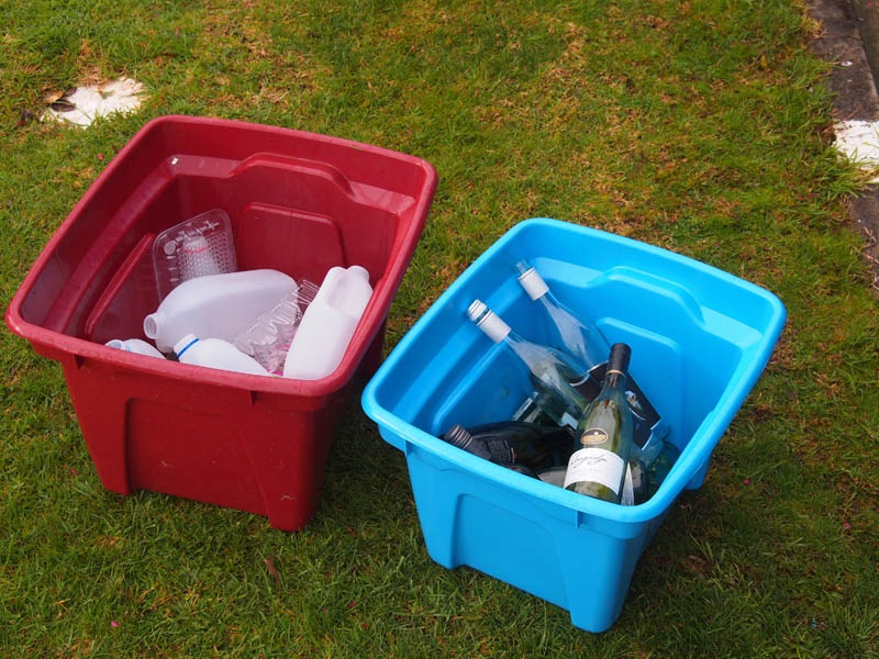 An image of a red and blue recycling bin provided for kerbside collection with plastics in the red bin and glass in the blue bin. 