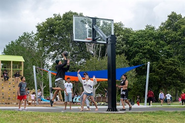 A group of teenagers play on the basketball half-court at Raumanga Scenic Reserve Playground.