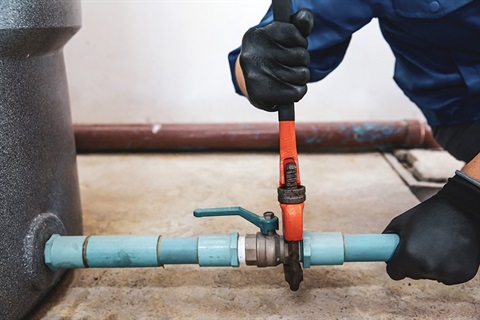 Photo of someone adjusting a pipe with a wrench. 