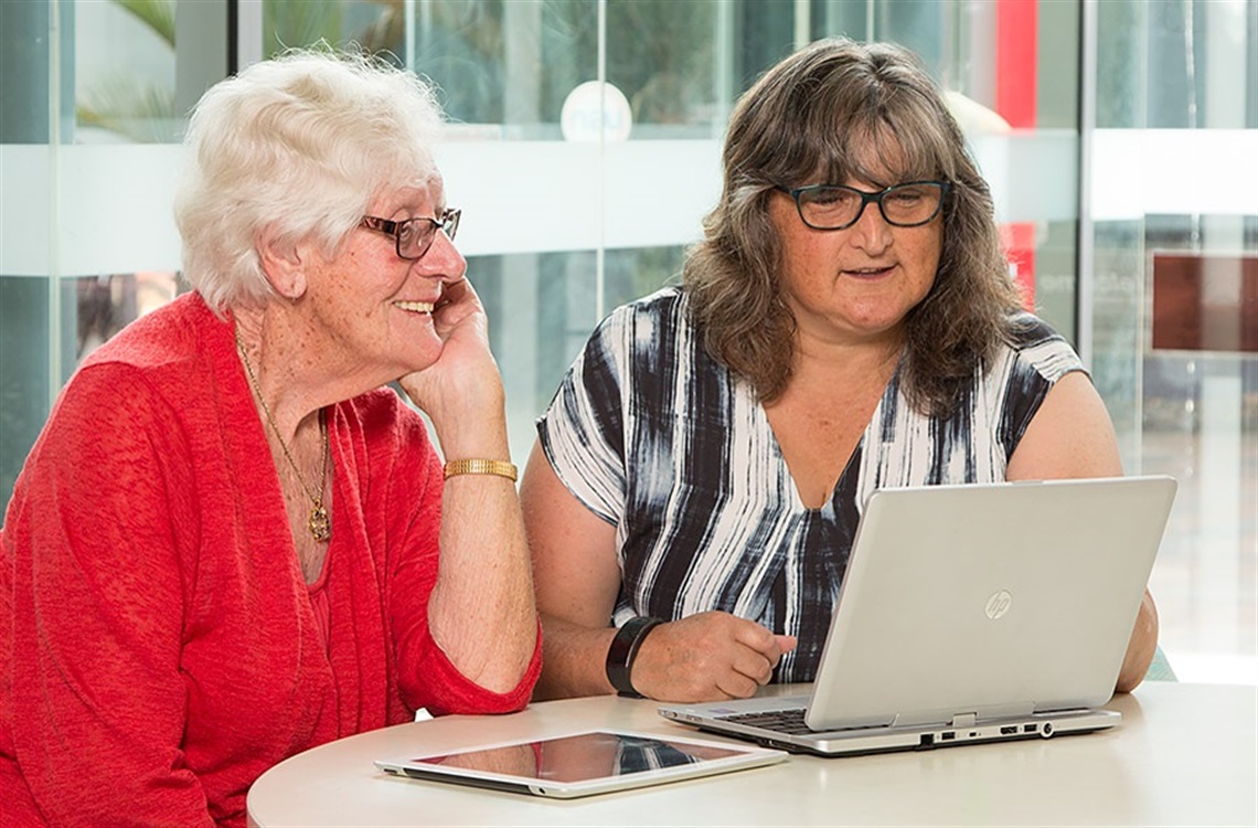 Image of a librarian helping an older women with her computer.  Image of a librarian helping an older women with her computer.
