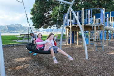 Children on the play equipment at the playground at Marsden Bay reserve, One Tree Point.