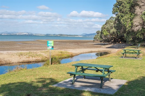 Photo showing picnic tables by the stream and beach at Tamaterau. 