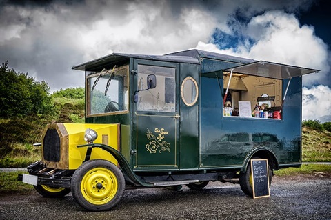 Old style mobile food truck, parked on the side of a road. 