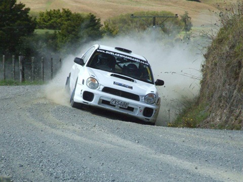 A white subaru car racing up a shingle road for a car club Hillclimb event. 