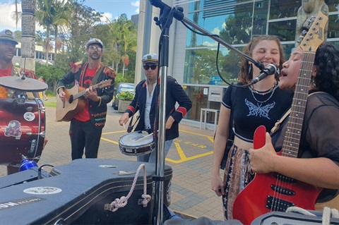 Musicians and performers playing instruments and singing outside of the Whangārei Central Library. 